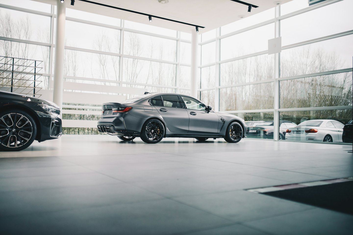A grey luxury sedan sits in a modern car dealership showroom.