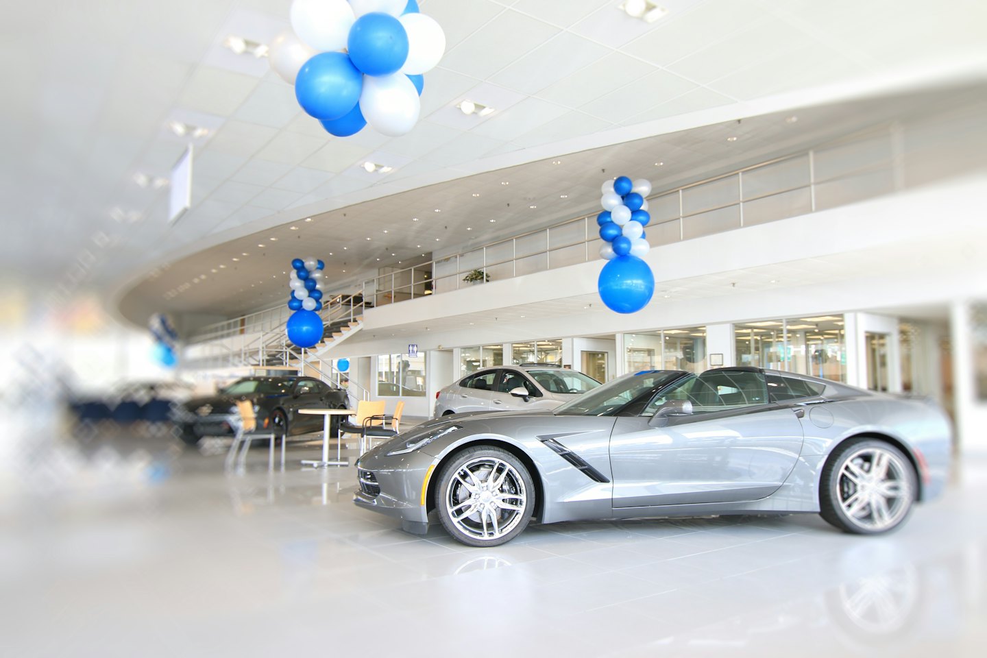 Shiny grey sports car in a modern car dealership showroom.